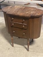 Full view of one Mary Washington table with three drawers and rounded sides showing top surface wear.
