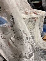 Close-up of a white lace tablecloth draped showing intricate floral and geometric crochet patterns