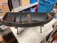 Side view of entire wooden boat on iron stand