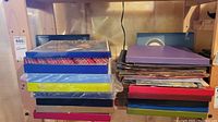 Stack of about 20 boxed set record albums on wooden shelf. Mix of colors with some shrink wrapped.