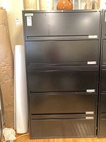 Full frontal view of the black metal filing cabinet showing all four drawers and the overall structure.