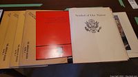 Seven military and national symbolism print booklets and folders, including 'Symbol of Our Nation' and 'Canada’s Military Heritage Collection.' Items laid out on a table, showing covers and condition.