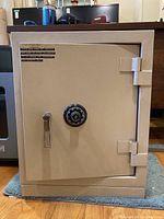 Front view of beige steel safe showing combination dial and handle