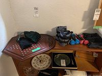 Two wooden game boards, one hexagonal for Chinese checkers with visible holes, and one for solitaire. Several workout weights including colorful mini dumbbells and Everlast ankle/wrist weights seen on a wooden cabinet surface.