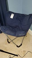 Blue canvas folding camp chair showing seat and frame with removable cushioned pad, placed on floor near wall.
