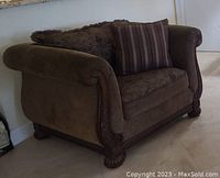 Front view of brown fabric armchair with two decorative pillows
