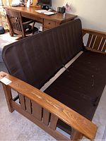 Futon frame showing wood armrests and brown mattress cover, top view.