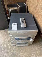 Photo showing the stereo unit with remote control on top and two speakers behind it