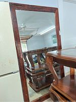 Front view of the large mirror leaning against a wall, showing the brown lacquered driftwood frame and reflective glass.