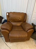 Front view of brown leather-like rocking recliner chair with cushioned arms and backrest.