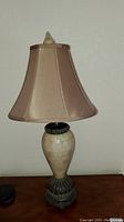 Single tan faux stone table lamp with metal base and beige fabric shade, shown unlit