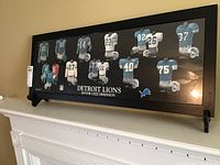 Framed print on stand showing uniforms from 1935 to 2000 with Detroit Lions logos and uniform numbers.