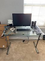Overview of glass-top desk showing HP all-in-one, keyboards, mouse, speakers and cables