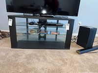 Full front view of the media stand with a flat screen TV on top and items on the shelves.