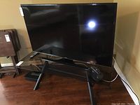 Front view showing Samsung TV, remote on shelf, and Timex clock radio