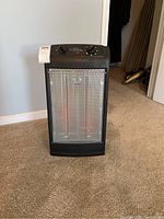 Front view of the black Conlin quartz radiant space heater standing upright on carpeted floor.