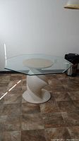 Front and side view of octagonal glass top table with unique spiral particle board pedestal base on tiled kitchen floor.