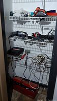 Closet shelves with various tools including Black & Decker Smart Driver, power tools, toolbox, and cords