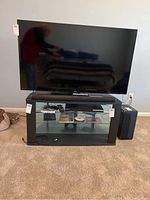 Full front view of the TV on stand with remote and antenna visible