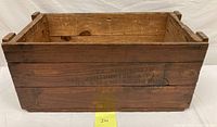 Front view of the wooden crate showing text stamped on the side and visible wear.