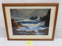 Frontal view of framed pastel seascape showing waves crashing on rocky shore under cloudy sky with artist signature visible on bottom right corner.