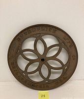 Full view of the circular cast iron wheel showing embossed text and flower petal openwork design.