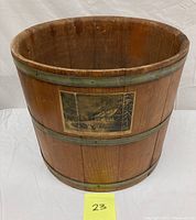 Wooden firkin bucket with three metal bands visible, vintage lithograph label on side featuring a cabin scene.
