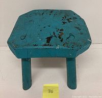 Top view showing rectangular plank seat with old blue paint and multiple areas of paint chipping and cracking.