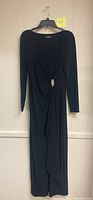 Full front view of a black Ralph Lauren stretch evening dress hanging on a hanger showing long sleeves and rhinestone clasp brooch detail at waist.