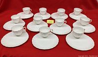 Full set of 22 pieces displayed on red cloth showing cups and saucers laid out.
