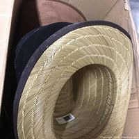 Close-up of natural woven straw cowboy hat showing texture and underside with barcode label.