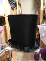 Tall black Coachman top hat with satin band.