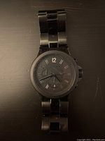 Front view of black Michael Kors men's wristwatch showing watch face with scratches and wear.