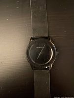 Close-up photo of the black Michael Kors watch face showing blank dial with no hour markers.