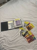 Photo showing black binder open with plastic sleeves holding Broadway playbills, and several loose playbills next to it including Hamilton and other shows