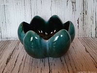Front angled view showing the lotus petal shaped ceramic planter with glossy green glaze.