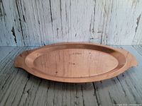 Small oblong copper tray displayed front view on rustic wooden surface, showing its full shape and patina.