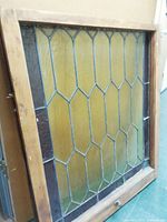Front view of antique leaded stained glass window showing geometric leaded pattern with clear and amber textured glass in wooden frame.