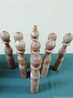 Nine wooden bowling pins arranged upright and one leaning on a green surface