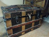 Exterior view of the trunk showing brass bindings, leather crocodile pattern, and wood panels with patina and wear.