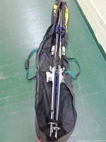 Full view of Rossignol skis laid out on a black tote bag with two blue and black ski poles.