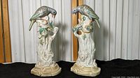 Two porcelain bird statues perched on detailed tree stump bases with hand painted leaves and flowers.