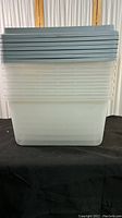 Stack of six clear plastic storage containers with blue lids, shown assembled one inside the other.