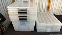 Stack of eight clear plastic storage containers with lids, showing overall lot contents.