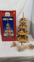 Photo of the complete wooden four-tiered pyramid with box and detached parts on white background.