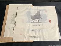 Stack of several Chinese paper rubbings with visible horse figure and red Chinese seals, ready for cataloging.