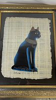 Front view of framed hand painted Pharoah cat artwork on papyrus, showing details of the cat and signature at bottom.