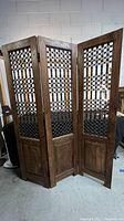 Full front view of the three-panel wooden and metal room divider standing open, showing each panel about 16 inches wide and 64 inches high.
