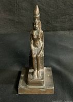Front view of bronze statue showing Isis seated on throne with detailed facial features and crown.