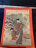 Print of woman and child outdoors, with calligraphy along the top on orange backing